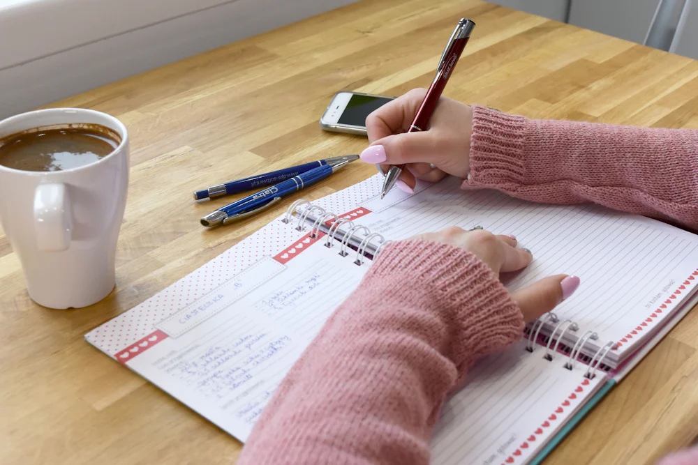 Agenda ouvert, stylo et tasse de café pour faire le point en début de journée